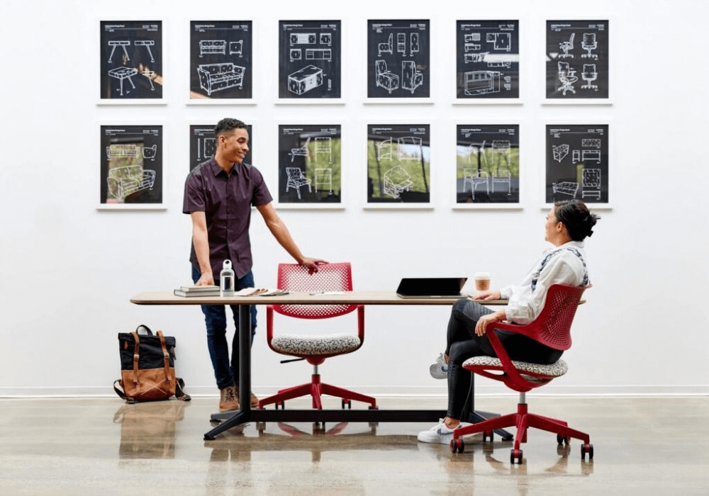 Two professionals discussing ergonomic office furniture at a modern workspace in NZ.